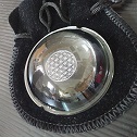 Result of laser engraving, Lense with engraved chakra motive. With velvet bag. On desk surface.